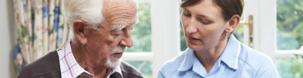 female carer helping senior man with medication