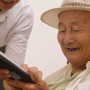 elderly man with a carer looking at mobile