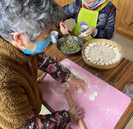 Two women in masks making dumplings Image
