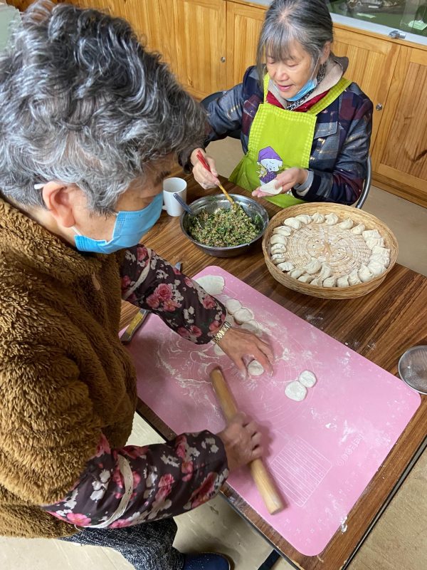 Two women in masks making dumplings
