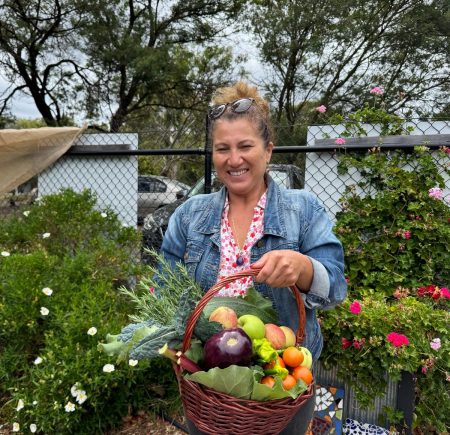 A woman holds a basket with a garden harvest Image