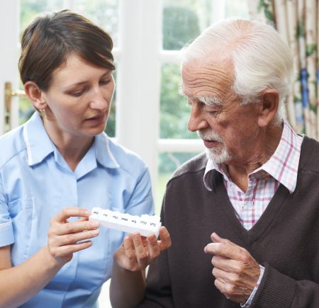 female carer helping senior man with medication