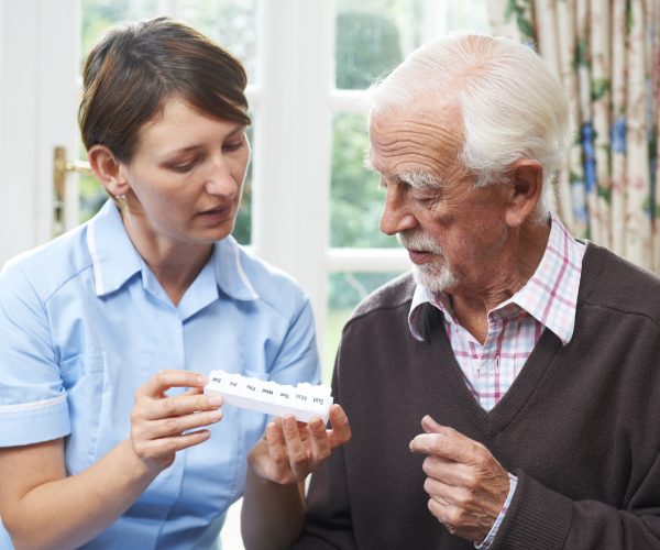 female carer helping senior man with medication