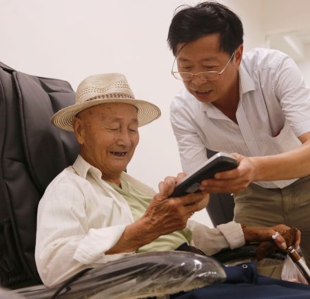 elderly man with a carer looking at mobile