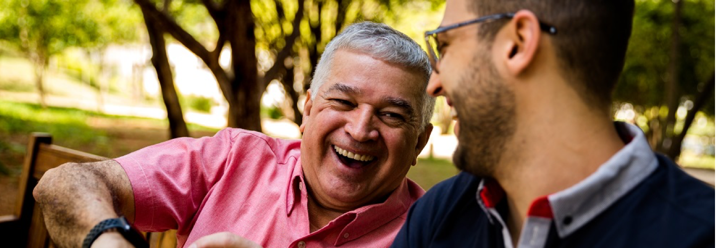 young man sitting with older man on park bench laughing