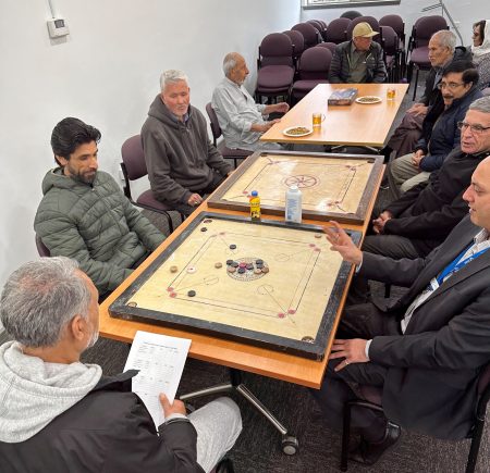 Men sitting around a table playing a game Image