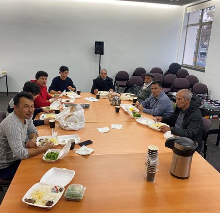 A group of men sitting around a large table eating a meal Image