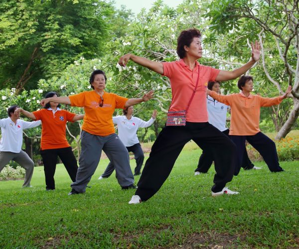 group of elderly asians doing tai chi outdoors