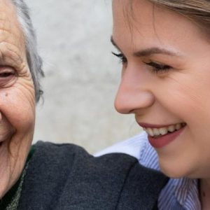 A young woman and an elderly woman smile together