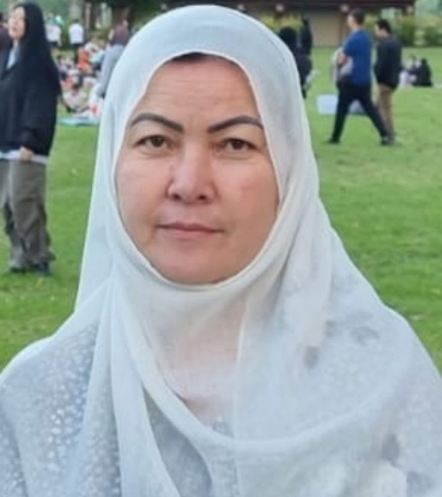 Sedqia, an Afghan woman, is wearing a white hijab and smiling softly at the camera.