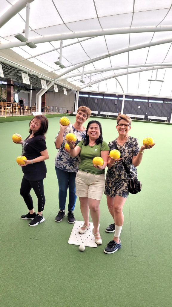 Four winners of the competition hold lawn bowls and smile at the camera