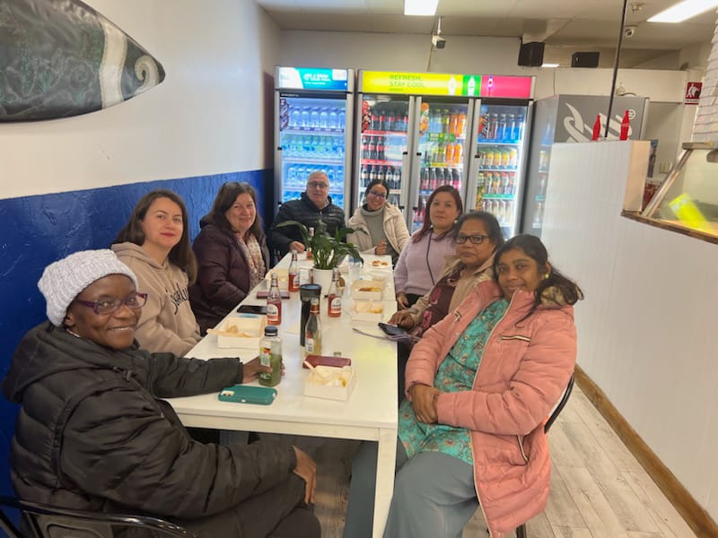 The group sitting at a long white table waiting for their lunch