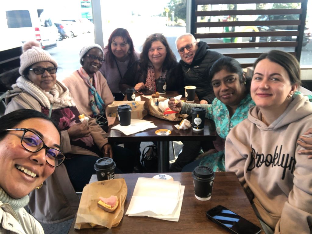 The group takes a smiley selfie with their coffees