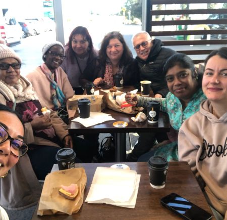 The group takes a smiley selfie with their coffee and breakfast Image