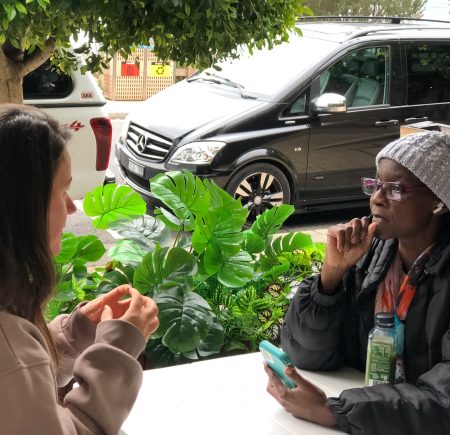 Two carers having a great chat at a table, there is a green plant in the background Image