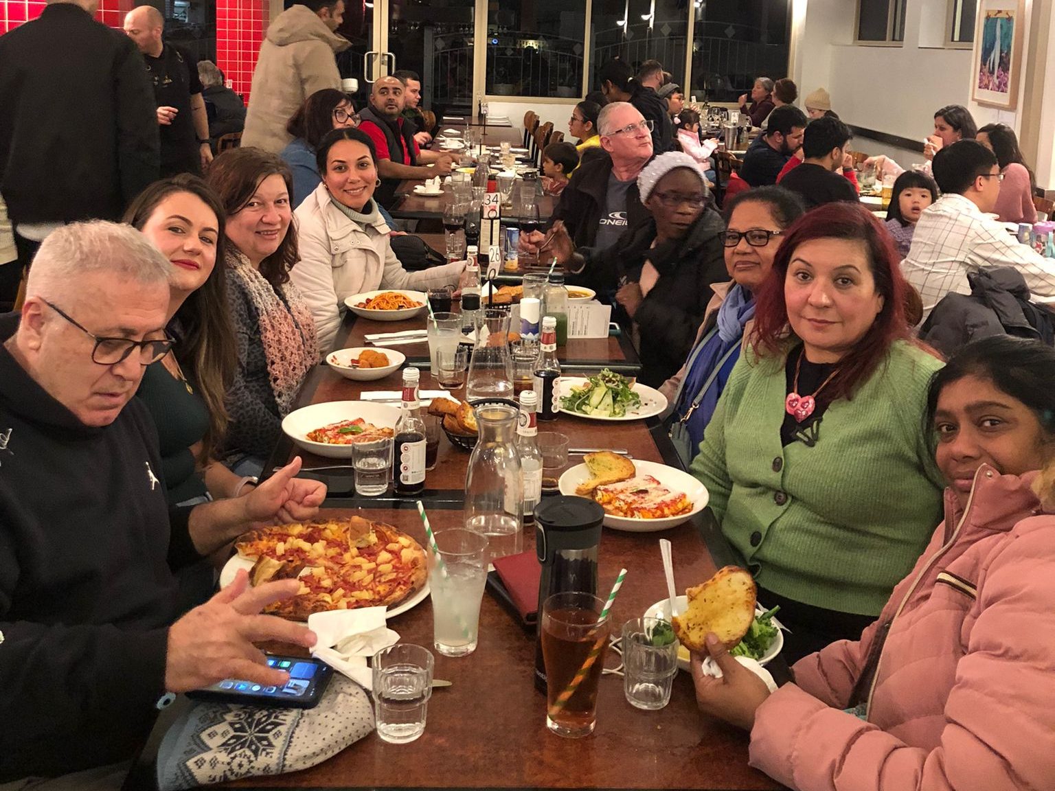 The group sits at a long wood table enjoying a variety of Italian food