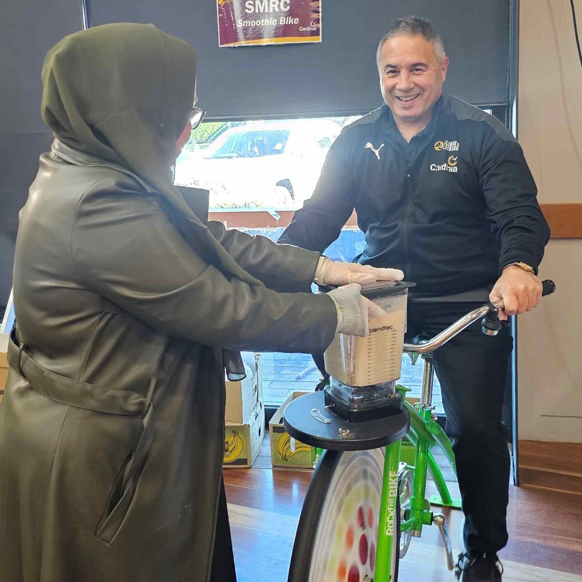 A man is on the SMRC smoothie bike which is green.
