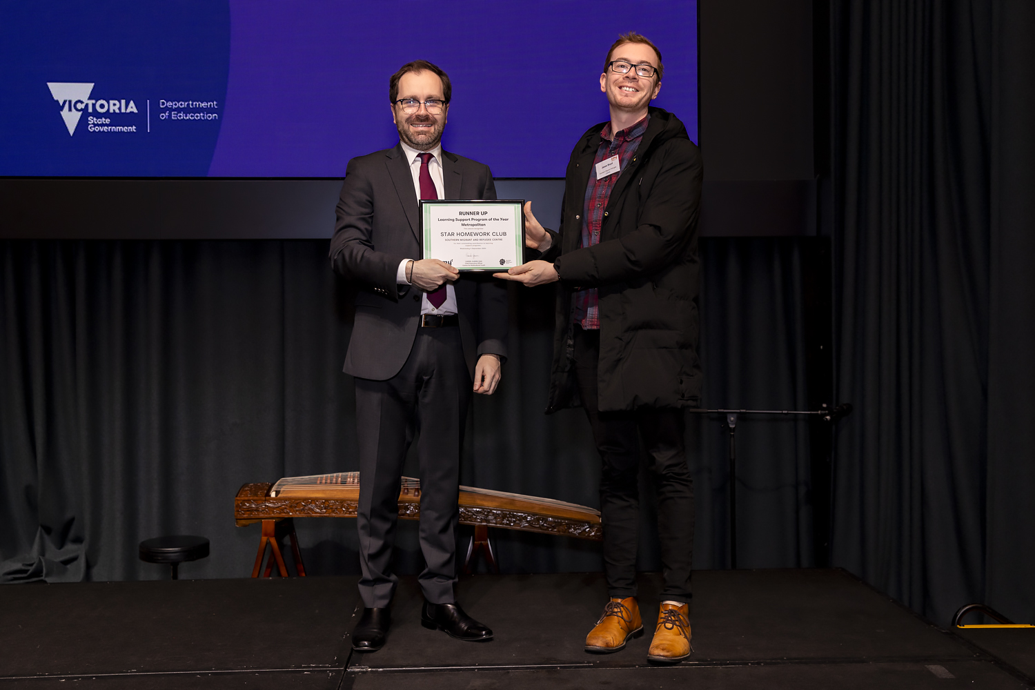 STAR Club Coordinator Jesse (left) stands on stage accepting the award