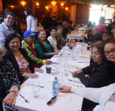 People sitting across a long white table smiling at the camera Image