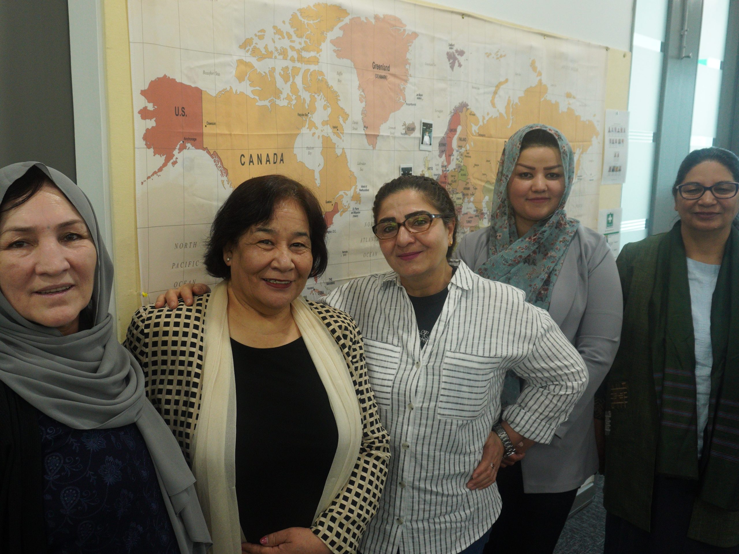 Five carers stand smiling at the camera