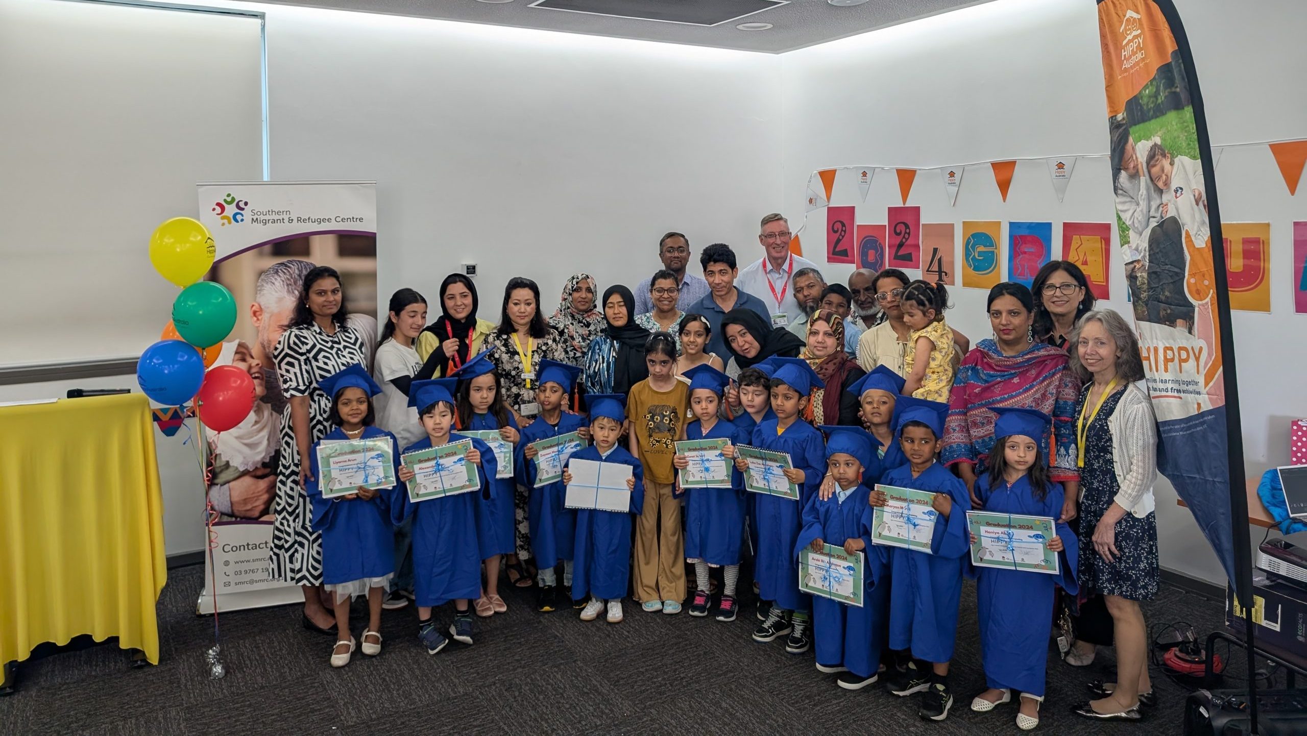 The HIPPY graduates and their families smile for a group photo.