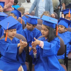 Two HIPPY graduates in blue gowns playing a game together