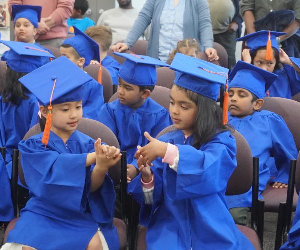Two HIPPY graduates in blue gowns playing a game together