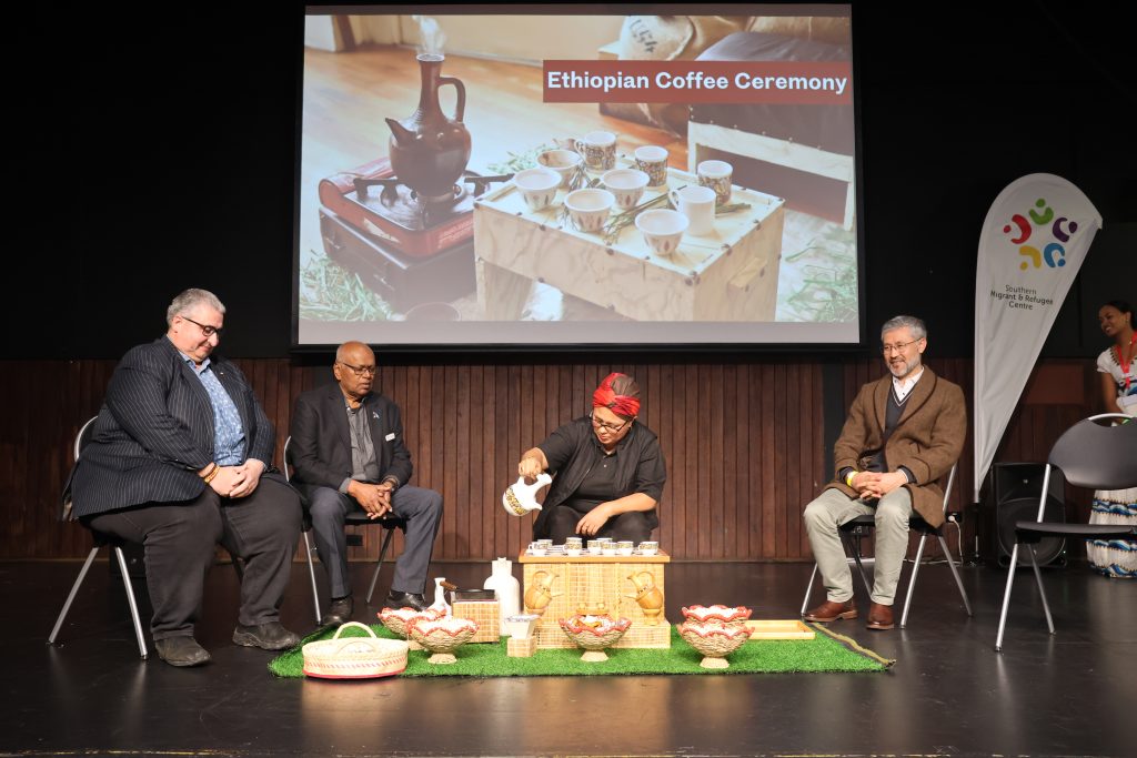 Four people sit on a stage and take part in an Ethiopian Coffee Ceremony