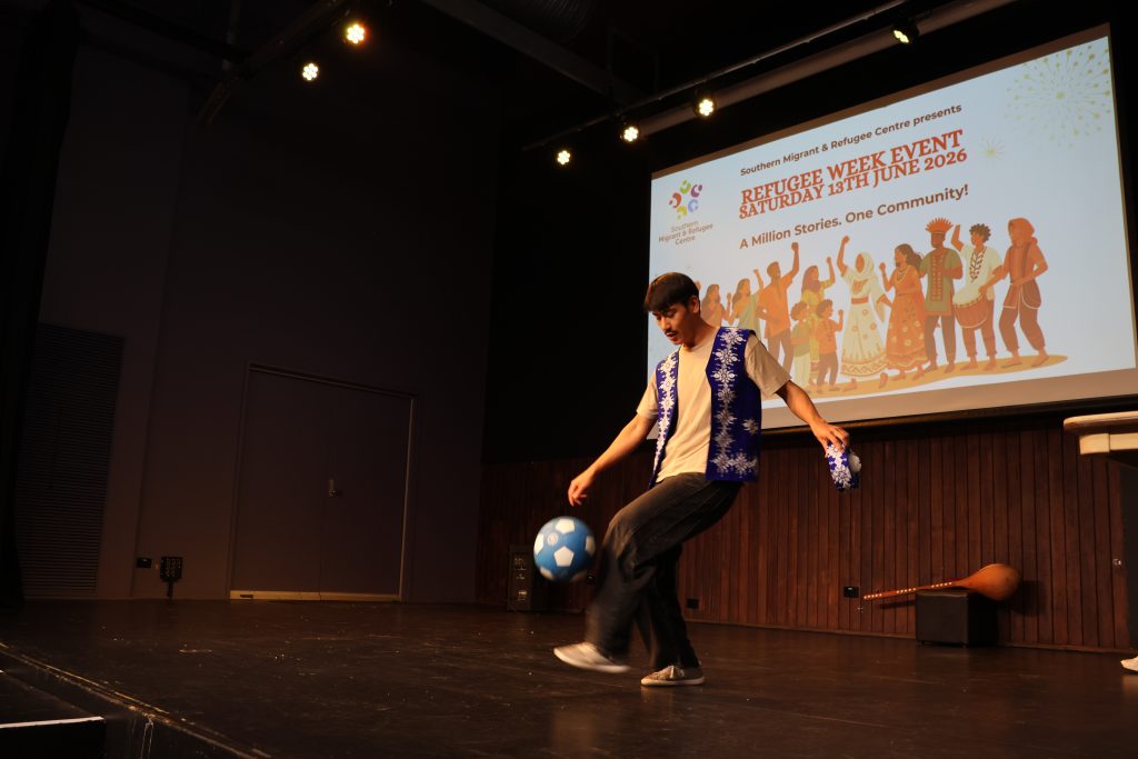 A young man on a stage kicks a soccer ball