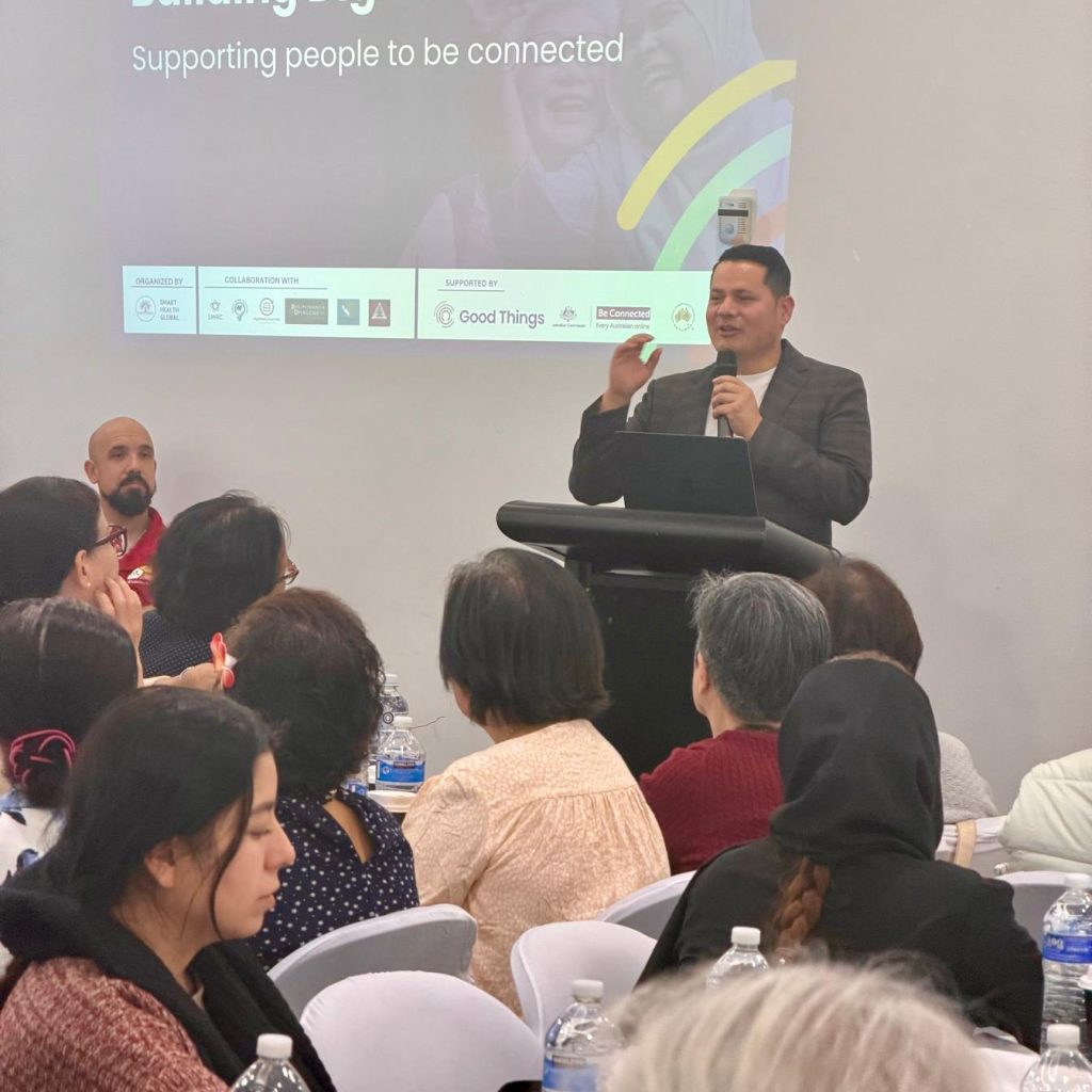 A man stands at a podium delivering a talk to a room of people